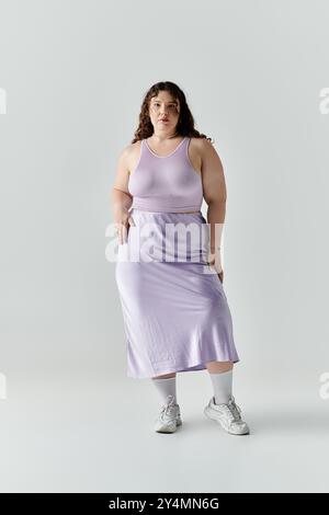 Eine schöne Frau in Übergröße zeigt ihre Eleganz in einem Lavendelkleid, das Selbstvertrauen ausstrahlt. Stockfoto