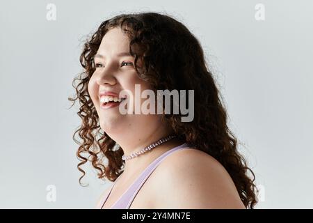 Eine fröhliche Frau in Übergröße strahlt Selbstvertrauen und Eleganz aus, während sie in sanftem Licht wunderschön lächelt. Stockfoto