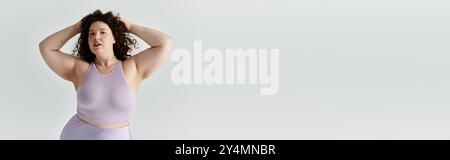 Eine schöne Frau in Übergröße zeigt ihr Selbstvertrauen und ihren Stil in einem weichen Pastellensemble. Stockfoto