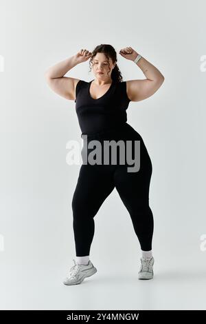 Eine schöne Frau in Übergröße zeigt ihre Anmut und Stärke in stylischer schwarzer Workout-Kleidung. Stockfoto