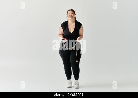 Eine selbstbewusste Frau in Übergröße strahlt Eleganz aus, während sie spielerisch ein Seil hält und Freude ausstrahlt. Stockfoto