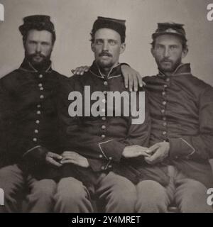 Drei unidentifizierte Unions-Soldaten sitzen zusammen und tragen charakteristische Uniformen. Stockfoto