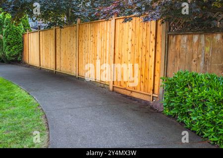 Großer neuer Holzzaun um das Haus und die Bäume. Harter Holzzaun mit grünen Bäumen und Weg. Zäune und Tore. Hochwertiger Zaun. Straßenfoto. Stockfoto