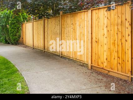 Großer neuer Holzzaun um das Haus und die Bäume. Harter Holzzaun mit grünen Bäumen und Weg. Zäune und Tore. Hochwertiger Zaun. Straßenfoto. Stockfoto