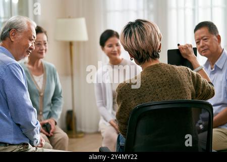 asiatische Beraterin, die eine Diskussionsrunde für eine Gruppe von Senioren leitet Stockfoto