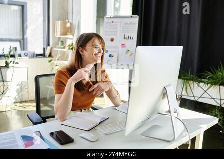 Eine nicht binäre Person lächelt beim Brainstorming an ihrem eleganten Schreibtisch. Stockfoto