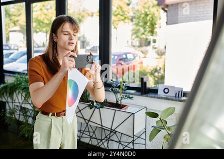 Ein junger, nicht binärer Mensch setzt sich im Büro mit bunten Designkonzepten auseinander. Stockfoto