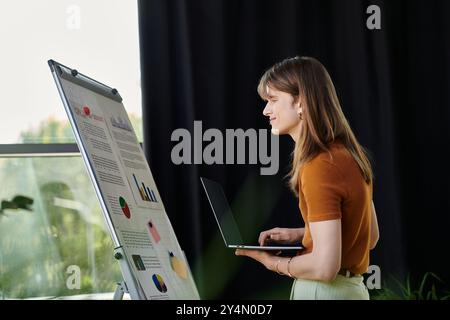 Eine junge, nicht binäre Person spricht ein Publikum mit einem Laptop und Präsentationsmaterialien an. Stockfoto