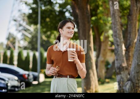 Die Person lächelt hell, während sie eine Kaffeetasse hält und einen sonnigen Arbeitstag genießt. Stockfoto