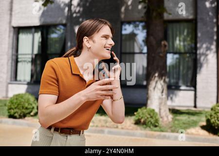 Eine junge, nicht binäre Person spricht gerne am Telefon und genießt den sonnigen Tag draußen. Stockfoto