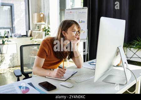 Eine junge, nicht binäre Person, die sich in kreativem Brainstorming engagiert, reflektiert während der Arbeit. Stockfoto