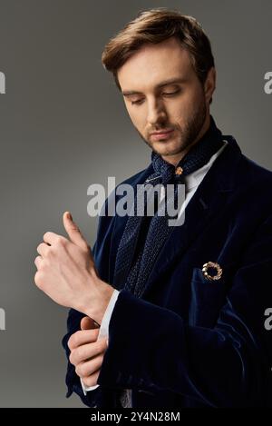 Ein gutaussehender Mann in einem raffinierten Outfit passt seine Manschettenknöpfe sorgfältig an. Stockfoto