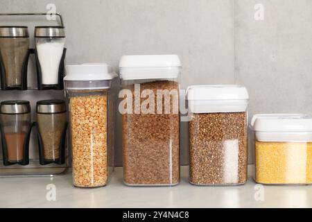 Verschiedene Arten von Getreide und Hülsenfrüchten in Behältern auf einem hellen Marmortisch Stockfoto