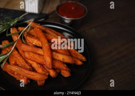 Süßkartoffelfritten, Rosmarin und Ketchup auf Holztisch, Nahaufnahme Stockfoto