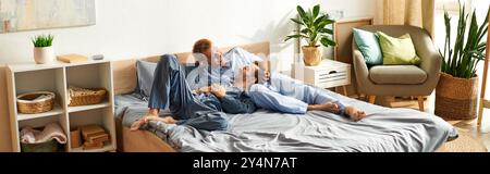 Ein glückliches schwules Paar entspannt sich im Bett und teilt an einem sonnigen Morgen Lachen und Wärme in ihrem Pyjama. Stockfoto