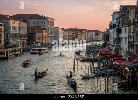 Blick von der Rialto-Brücke auf Gondoliere, die auf dem Canal Grande mit Touristen bei Sonnenuntergang in Venedig Italien Europa rudern Stockfoto