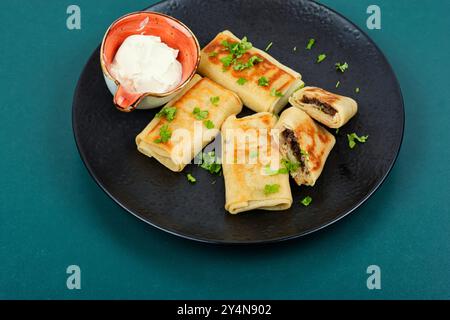 Köstliche Pfannkuchen oder Crepes gefüllt mit Rinderleber auf einem Teller. Pfannkuchentag. Stockfoto