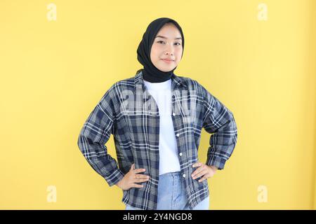 Asiatische junge Frau in Casual Fashion und Hijab, die sich selbstbewusst fühlt und mit Hand auf Hüften steht Stockfoto