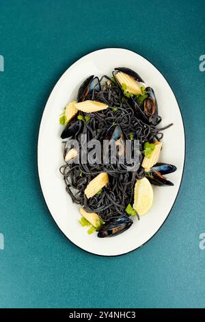 Schwarze Nudeln mit Meeresfrüchten und Muscheln auf weißem Teller. Draufsicht. Mediterrane Pasta Vongole. Stockfoto