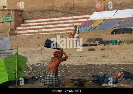 Varanasi, Uttar Pradesh / Indien - 9. Mai 2015 : morgens wird die Wäsche vom Waschmann im Wasser des Ganges bei Varanasi GHA gewaschen Stockfoto