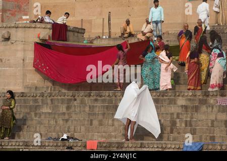 Varanasi, Uttar Pradesh / Indien - 9. Mai 2015 : Eine Gruppe von Pilgerinnen an der Küste von Varanasi ist damit beschäftigt, ihre Sarees in der Sonne zu trocknen. Stockfoto