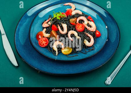 Vegetarische Spaghetti-Pasta mit Garnelen und Tomaten. Schwarze Nudeln. Gesundes Lebensmittelkonzept. Stockfoto