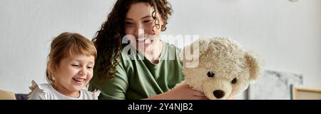 Ein lebendiger Moment einer übergroßen Mutter und ihrer Tochter, die gemeinsam mit einem Teddybären spielen. Stockfoto