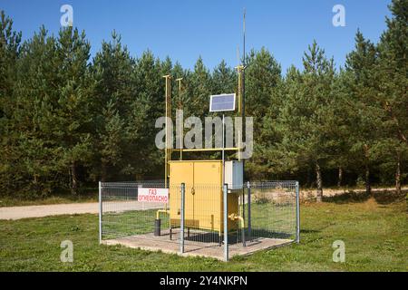 Regelungs- und Verteilungspunkt für Erdgas mit Solarbatterie in der Nähe von Kiefernwäldern, sonnigem Tag. Gaszufuhr zum Verbraucherschrank. Russischer Text - Stockfoto