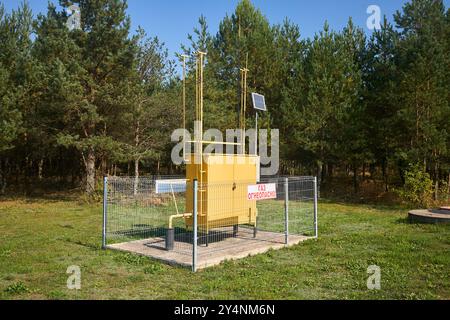 Regelungs- und Verteilungspunkt für Erdgas mit Solarbatterie in der Nähe von Kiefernwäldern, sonnigem Tag. Gaszufuhr zum Verbraucherschrank. Russischer Text - Stockfoto