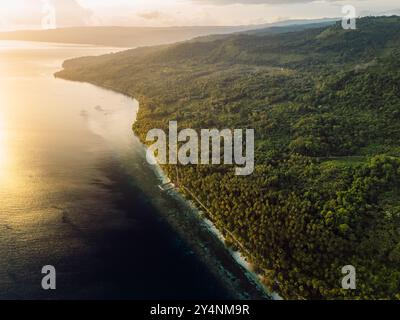 Paradiesische Küstenlandschaft mit Bergen und Sonnenaufgangssonne auf einer malerischen tropischen Insel in Indonesien. Reiseziel-Konzept. Stockfoto