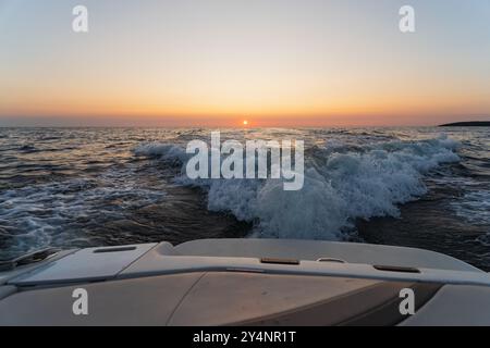 Ein schnelles Segelboot bei Sonnenuntergang im Meer, Foto von hinten. Ein Foto mit einem verstreuten Horizont als kreative Technik. Stockfoto