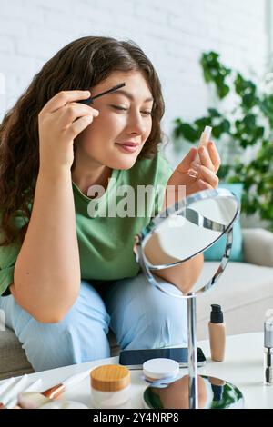 Eine junge Frau in lockiger Größe schminkt sich in einem gemütlichen Wohnzimmer, umgeben von Schönheitsprodukten. Stockfoto