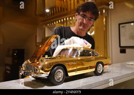 James Franks, CEO von Agora Models, poliert ein 24-karätiges vergoldetes Modell von James Bond's Goldfinger Aston Martin DB5 mit einem Preis von £24.999 und eines von nur sieben Exemplaren, die von den britischen Automobilhersteller Agora Models in Museumsqualität im Maßstab 1:8 hergestellt wurden. Das Modell wurde in Zusammenarbeit mit 007 Filmemachern, Eon Productions und Aston Martin zur Feier des 60-jährigen James-Bond-Films Goldfinger aus dem Jahr 1964 entwickelt. Es enthält einige der berühmtesten Gadgets von Bond, darunter einen funktionierenden Ejektorsitz und ein drehbares Nummernschild. Bilddatum: Donnerstag, 19. September 2024. Stockfoto