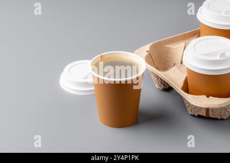 Warmer Kaffee in einer braunen Papiertasse auf grauer Oberfläche mit einem Tablett Stockfoto