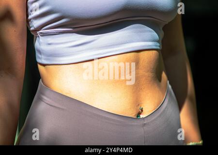 Eine FIT-Enthusiast von Pilates zeigt ihre gestrafften bauchmuskeln, während sie einen schlanken Fitnessanzug trägt, der die Kraft und das Kerntraining unterstreicht. Stockfoto