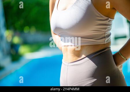 Eine FIT-Enthusiast von Pilates zeigt ihre gestrafften bauchmuskeln, während sie einen schlanken Fitnessanzug trägt, der die Kraft und das Kerntraining unterstreicht. Stockfoto