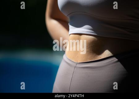 Eine FIT-Enthusiast von Pilates zeigt ihre gestrafften bauchmuskeln, während sie einen schlanken Fitnessanzug trägt, der die Kraft und das Kerntraining unterstreicht. Stockfoto