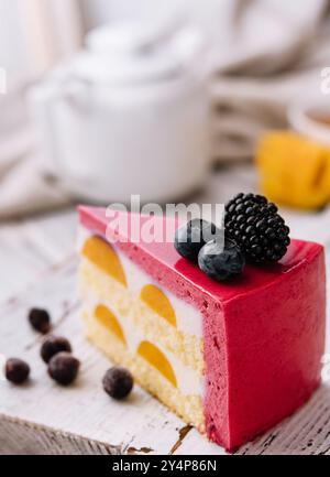 Ein Stück eines rosafarbenen Erdbeerkäsekuchens, serviert mit frischen Beeren auf einer weißen Tafel Stockfoto