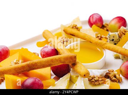 Käseplatte mit Honig, Nüssen und roten Trauben Stockfoto