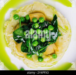 Kartoffelpüree mit Butter, grünen Erbsen, Basilikum in einer weißen Schüssel Stockfoto