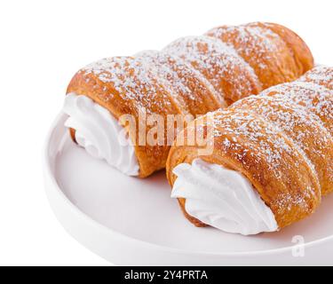 Gebackene Röhrchen mit Schlagsahne auf Teller Stockfoto