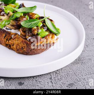 Toast mit gebratenen Stachelpilzen auf weißem Teller Stockfoto