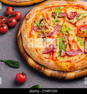 Gebackene runde Pizza mit Salami, Tomaten und Pilzen Stockfoto