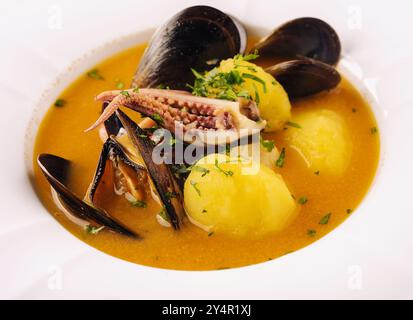 Cremige Meeresfrüchte-Suppe mit Muscheln, Kartoffeln und kleinen Tintenfischen Stockfoto