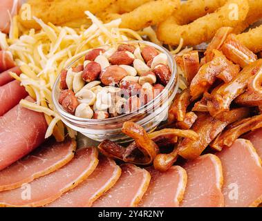 Getrocknetes Rindfleisch, gebratene Schweineohren, Zwiebelringe, Calamari, Nüsse, auf einer Platte Stockfoto