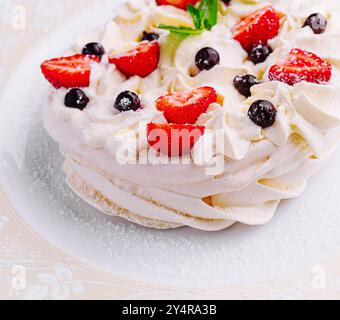 Pavlova-Kuchen mit Sahne und frischen Beeren auf Teller Stockfoto