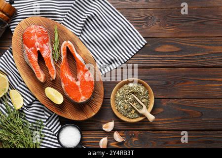 Brett mit frischen Lachssteaks, Gewürzen, Kräutern und Zitrone auf Holztisch, flach gelegt. Leerzeichen für Text Stockfoto