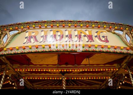 Das bemalte Schild auf einem Karussell auf dem Dampfmarkt zeigt das Wort „Reiten“ Stockfoto