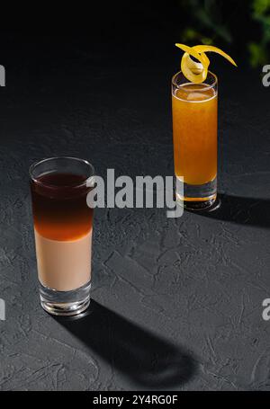 Zwei verschiedene Shots mit alkoholischen Cocktails auf dunklem Stein Stockfoto