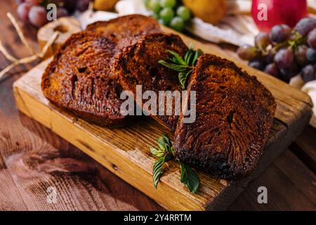 Ein Schuss frisch gebackener Brownies mit frischen Kräutern, serviert mit Trauben auf einem rustikalen Brett Stockfoto